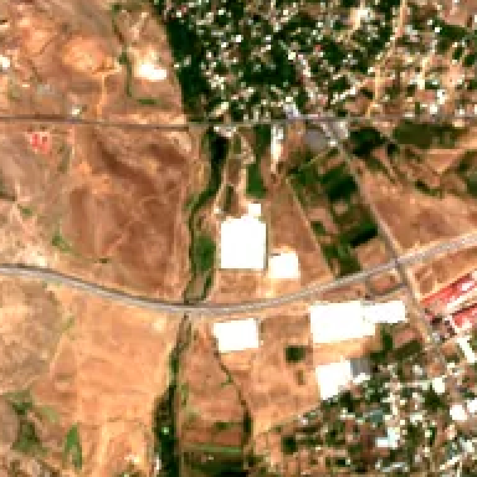 Supplied Aragats satellite image with bright roof-like features beside a road.
